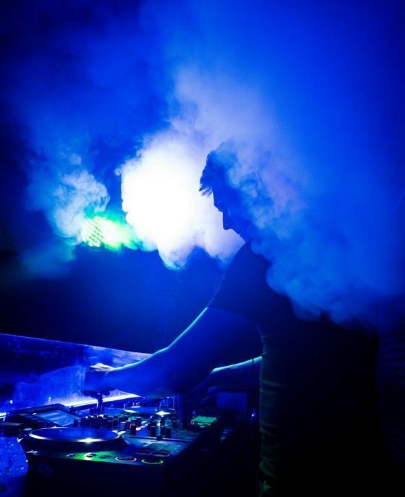 Humo y luces azules sobre la mesa de mezclas en el club