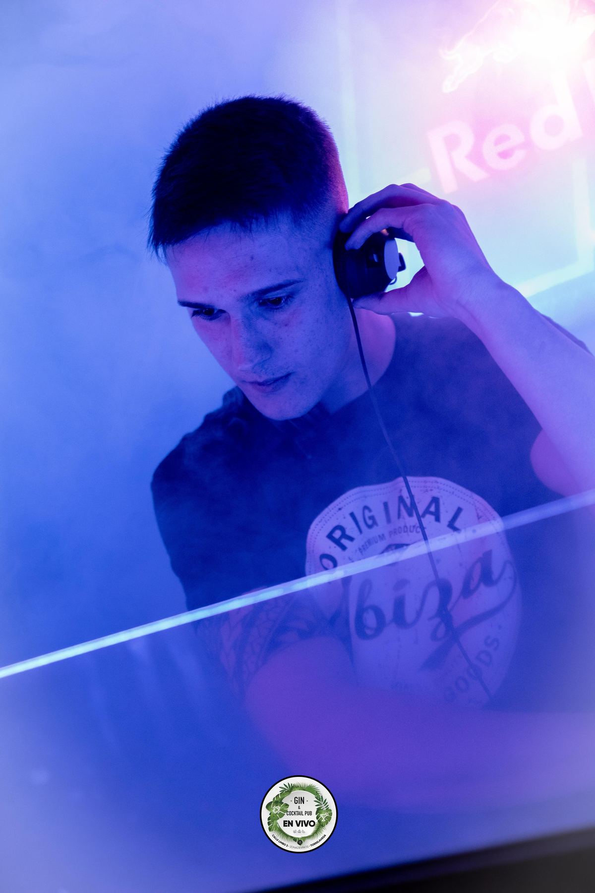DJ Robles con auriculares bajo luces azules intensas en un club